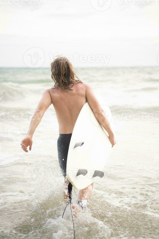 Surfer man with his surfboard on the beach. photo