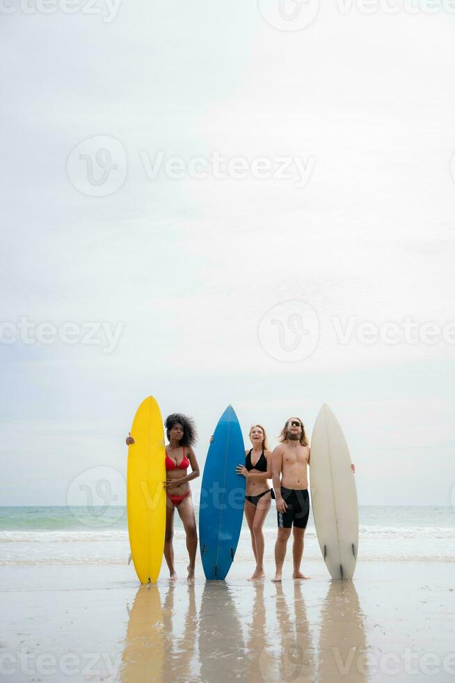 Group of friends in swimsuits posing with surfboards on the beach. photo