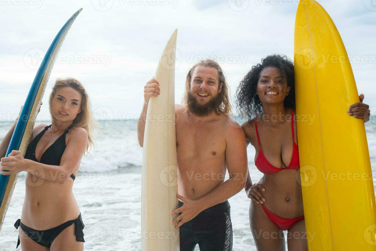 Two women and young man holding surfboards ready to walk into the sea to surf. photo