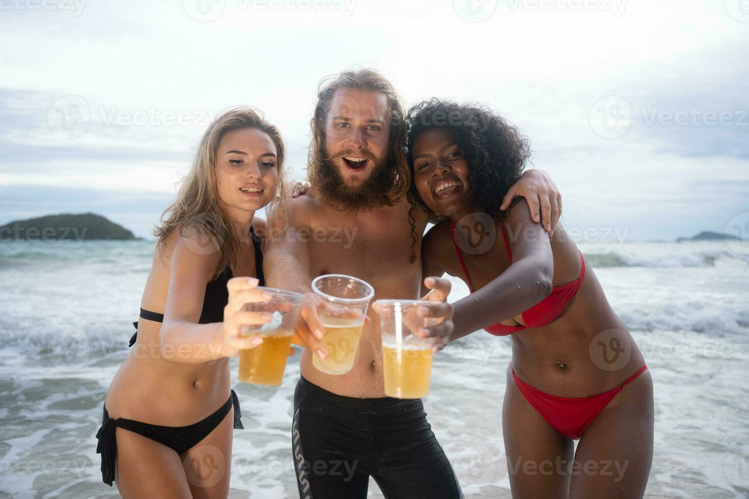 Multi-ethnic group of friends having fun on the beach, drinking beer and having fun photo