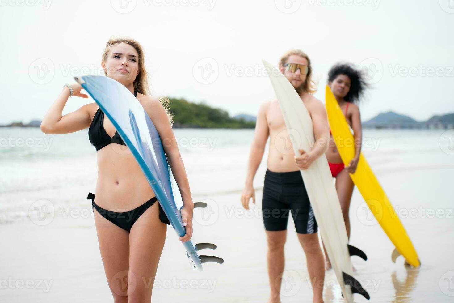 Two women and young man holding surfboards ready to walk into the sea to surf. photo