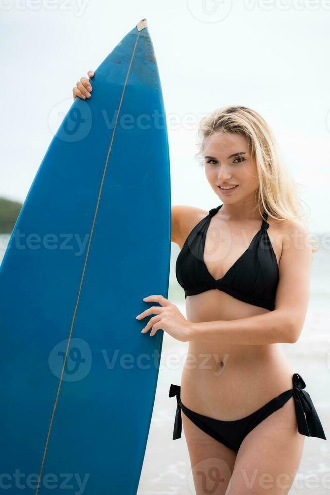 Surfer girl with her surfboard on the beach. photo