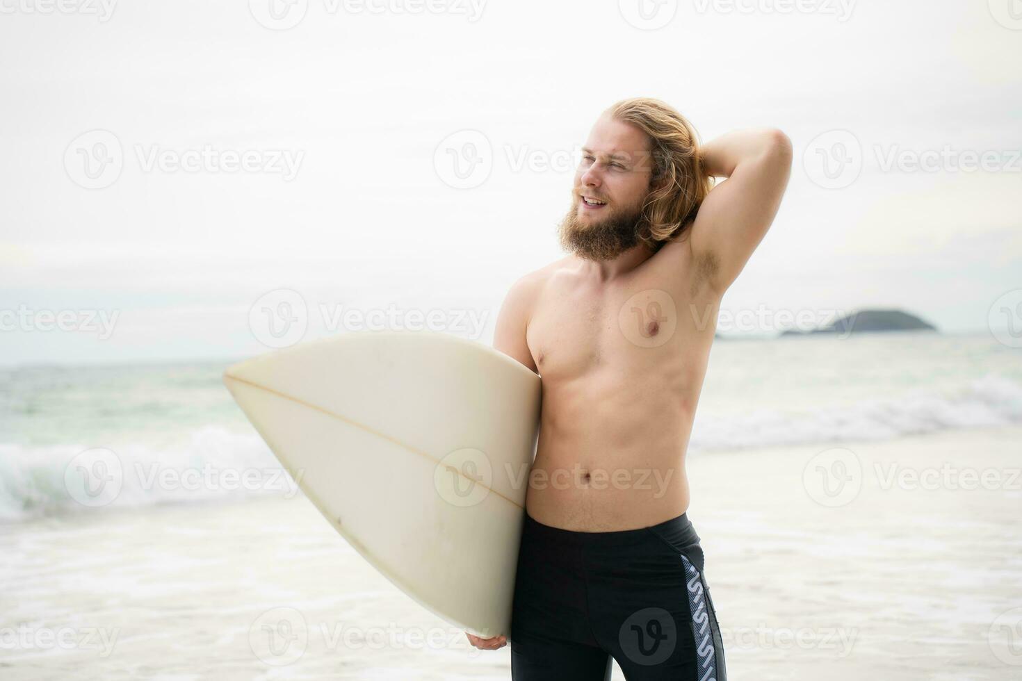 Surfer man with his surfboard on the beach. photo