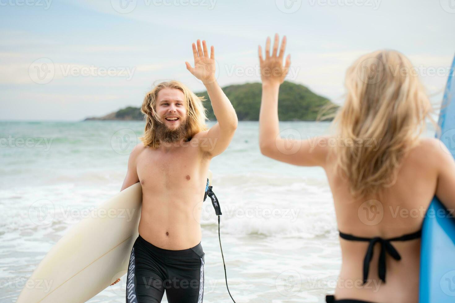 Two surfers giving high five on the beach. Two surfers having fun on the beach. photo