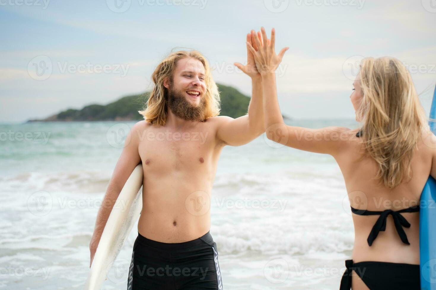 Two surfers giving high five on the beach. Two surfers having fun on the beach. photo