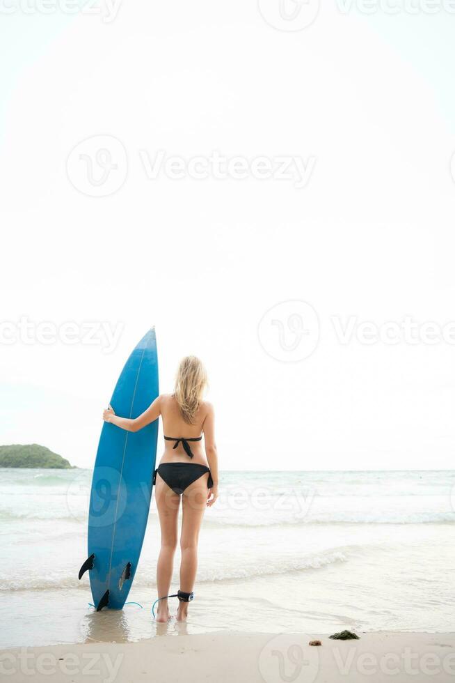 Surfer girl with her surfboard on the beach. photo