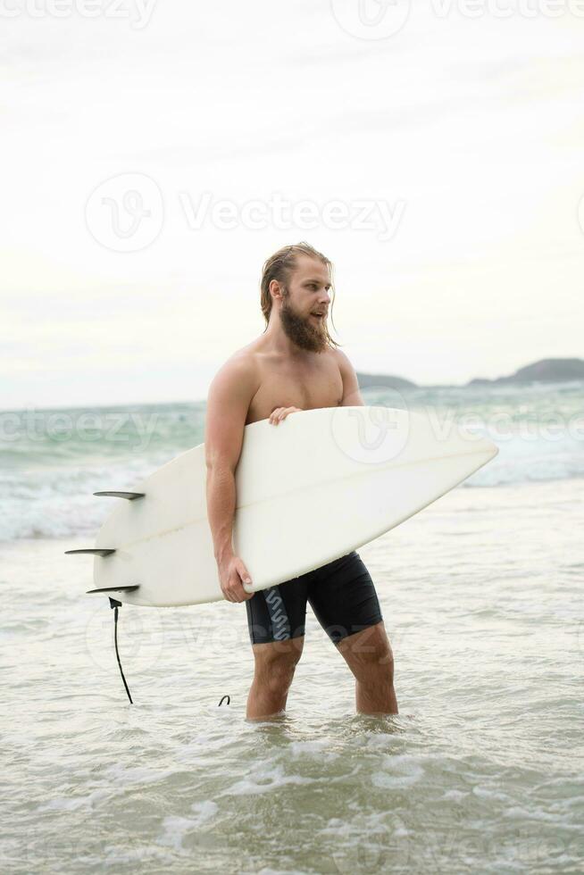 Surfer man with his surfboard on the beach. photo