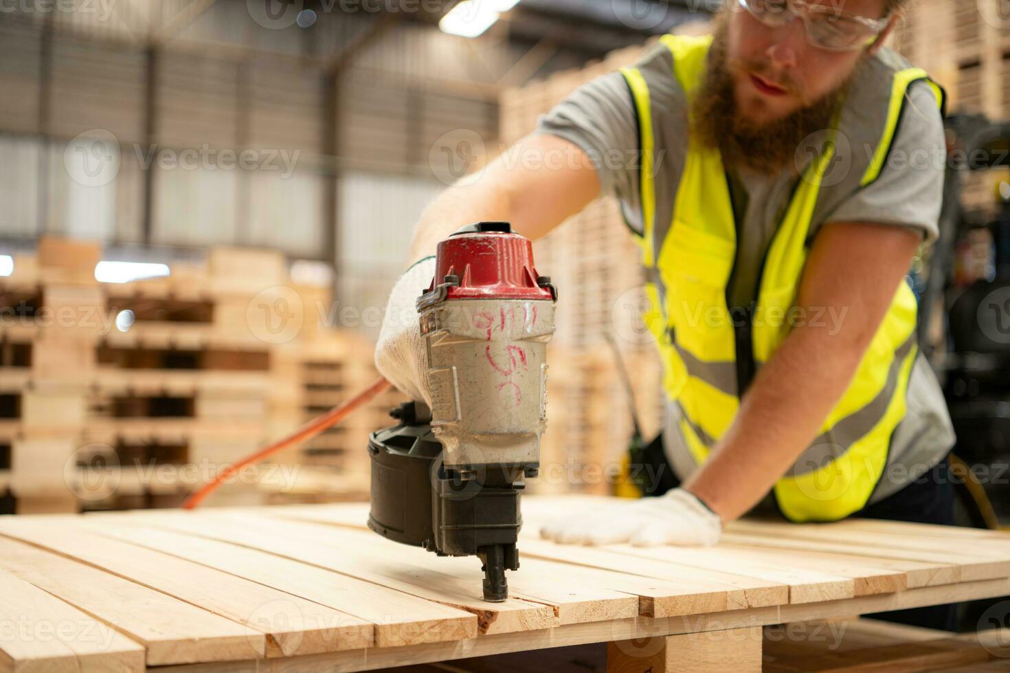 Young workers working in a woodworking factory, Using a nailing machine to assemble wooden pallets photo