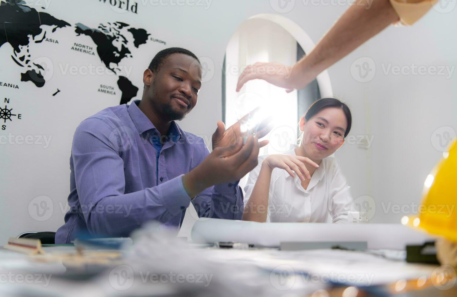 Multiethnic team of architects and designers are meeting new project, He carries a light bulb that should not be used in buildings because it is not energy efficient and not earth-friendly. photo