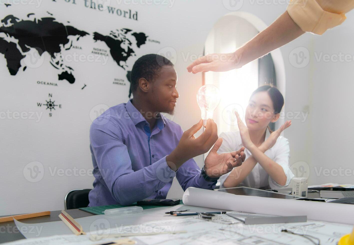 Multiethnic team of architects and designers are meeting new project, He carries a light bulb that should not be used in buildings because it is not energy efficient and not earth-friendly. photo