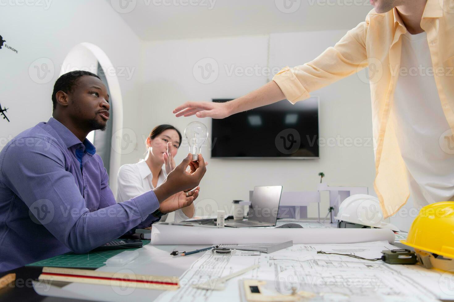 Multiethnic team of architects and designers are meeting new project, He carries a light bulb that should not be used in buildings because it is not energy efficient and not earth-friendly. photo