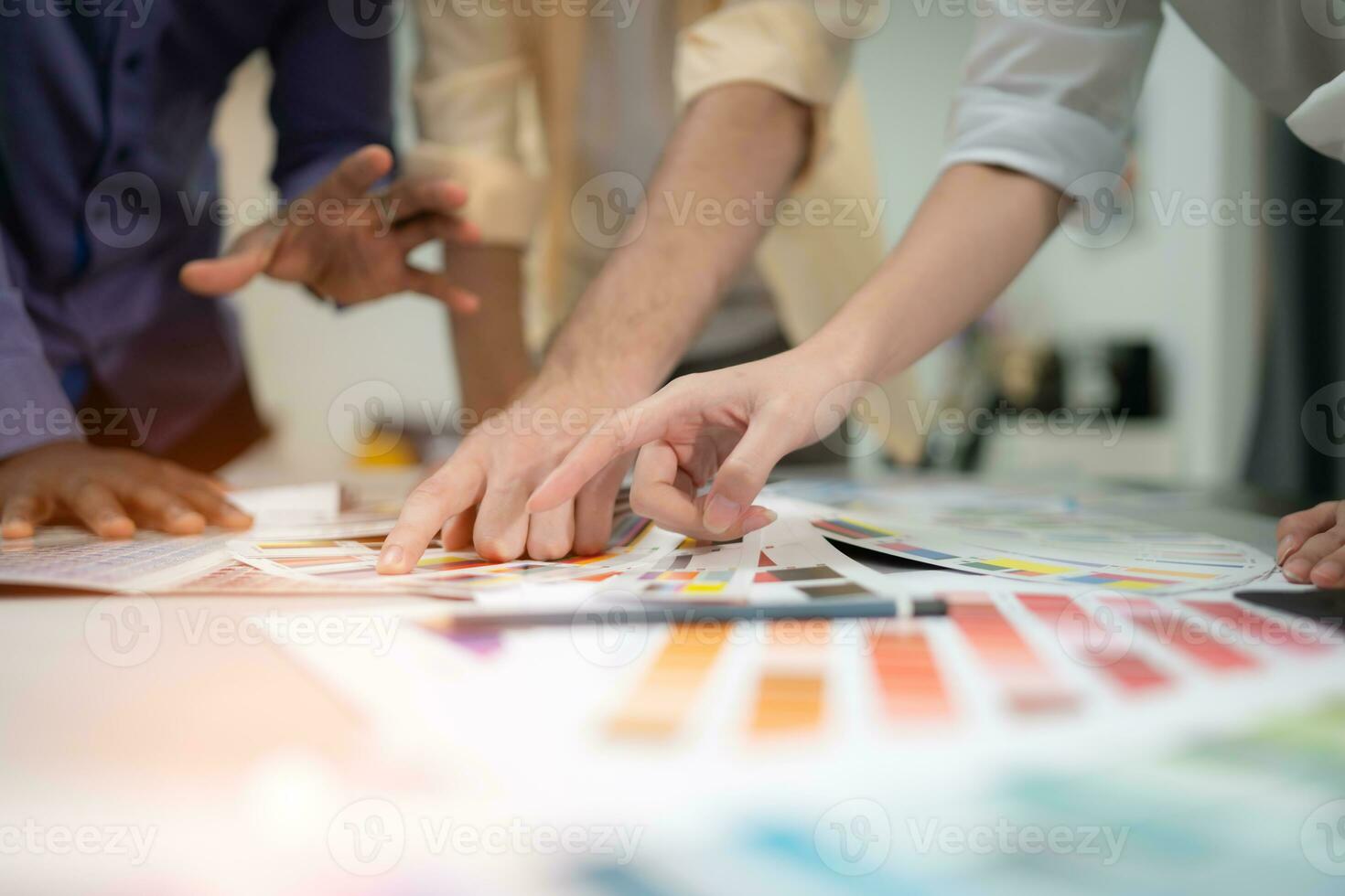 Multiethnic team of architects and designers are meeting to brainstorm design an application smartphone on a bright modern office working on a laptop. photo