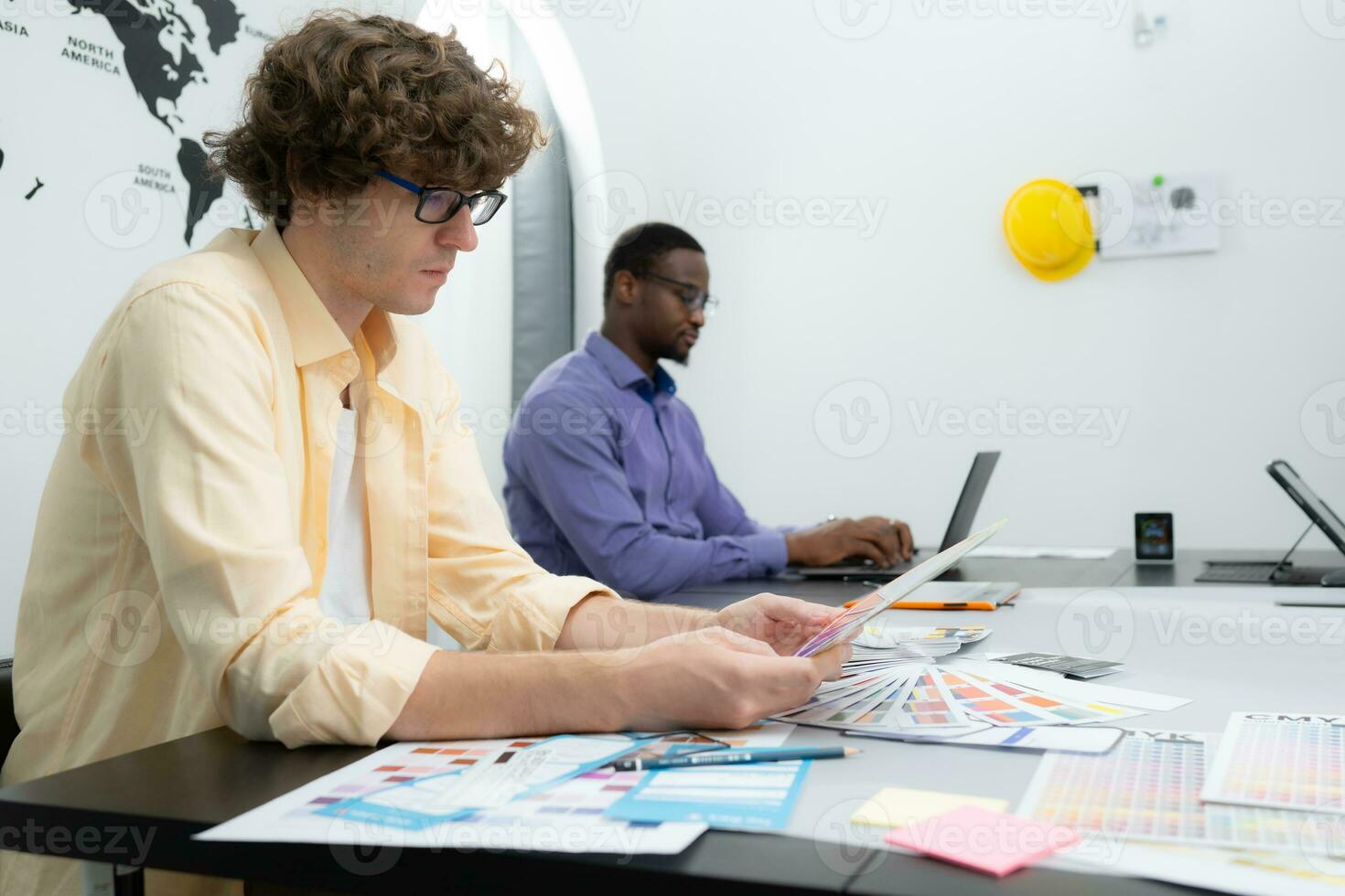 Multiethnic team of architects and designers are meeting to brainstorm design an application smartphone on a bright modern office working on a laptop. photo
