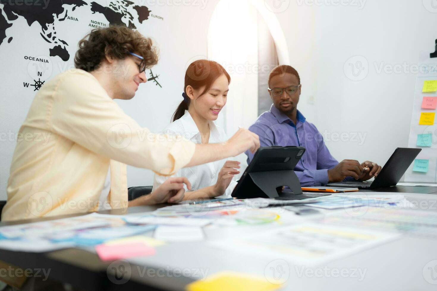 Multiethnic team of architects and designers are meeting to brainstorm design an application smartphone on a bright modern office working on a laptop. photo