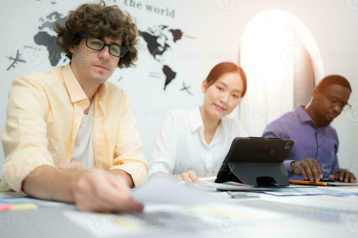 Multiethnic team of architects and designers are meeting to brainstorm design an application smartphone on a bright modern office working on a laptop. photo