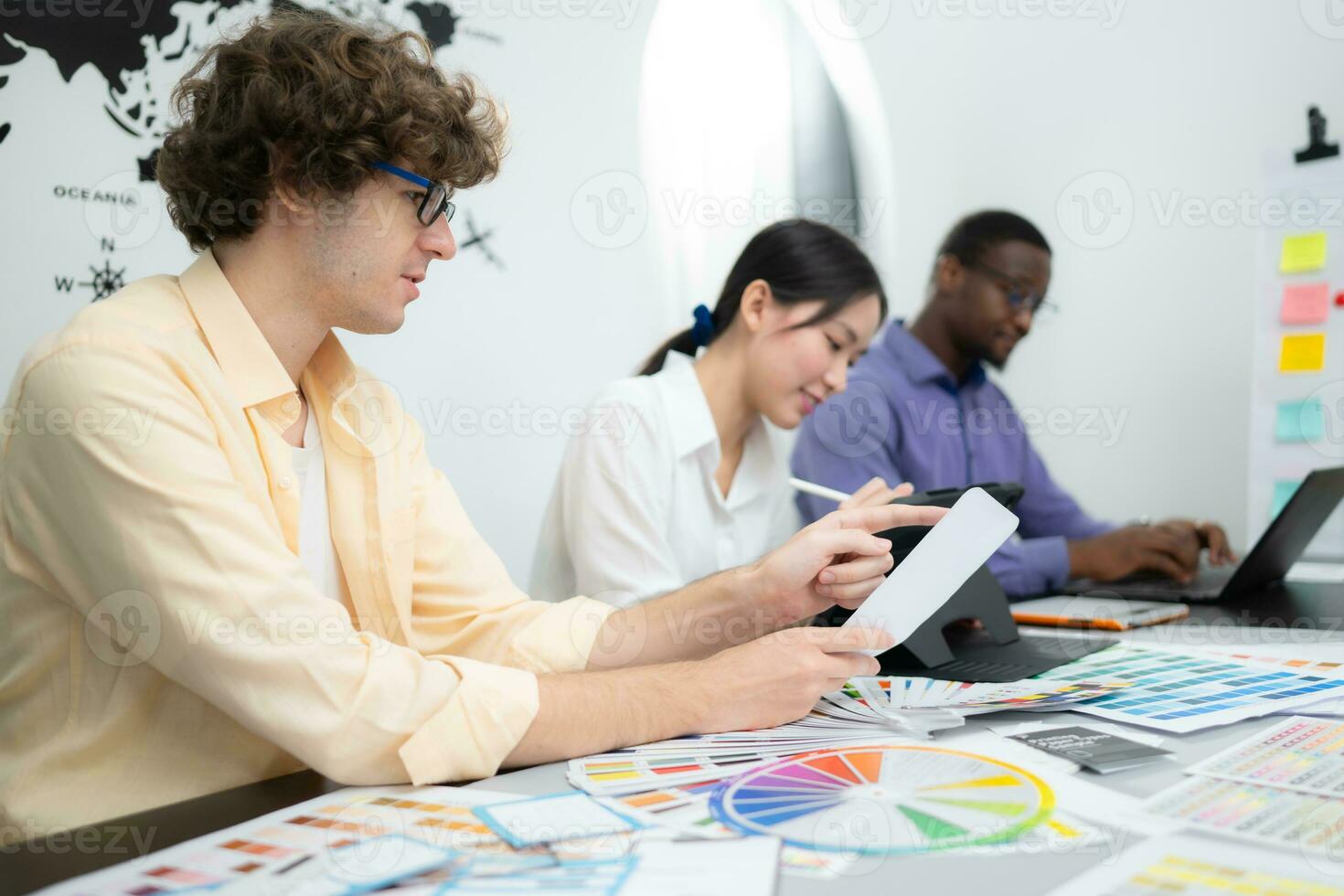 Multiethnic team of architects and designers are meeting to brainstorm design an application smartphone on a bright modern office working on a laptop. photo