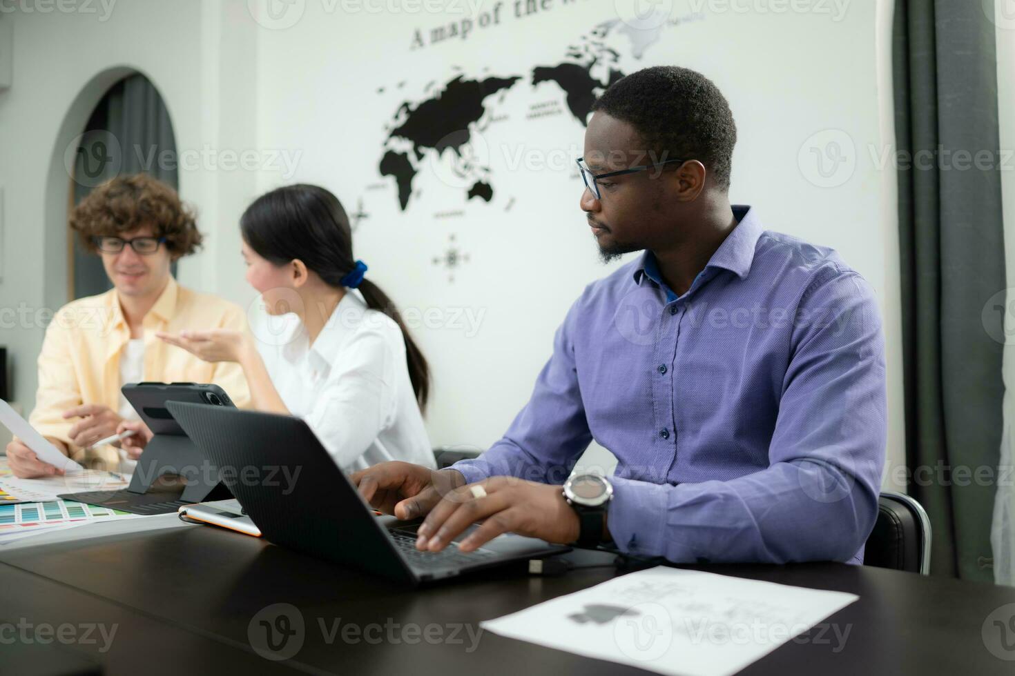 Multiethnic team of architects and designers are meeting to brainstorm design an application smartphone on a bright modern office working on a laptop. photo