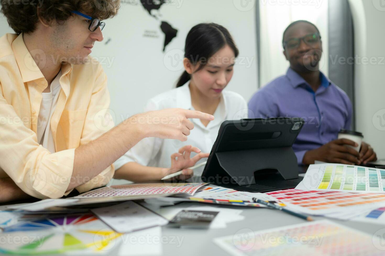 Multiethnic team of architects and designers are meeting to brainstorm design an application smartphone on a bright modern office working on a laptop. photo