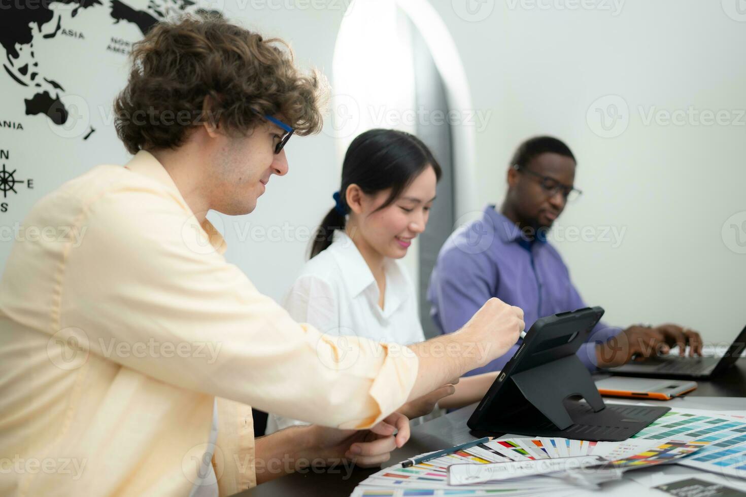 Multiethnic team of architects and designers are meeting to brainstorm design an application smartphone on a bright modern office working on a laptop. photo