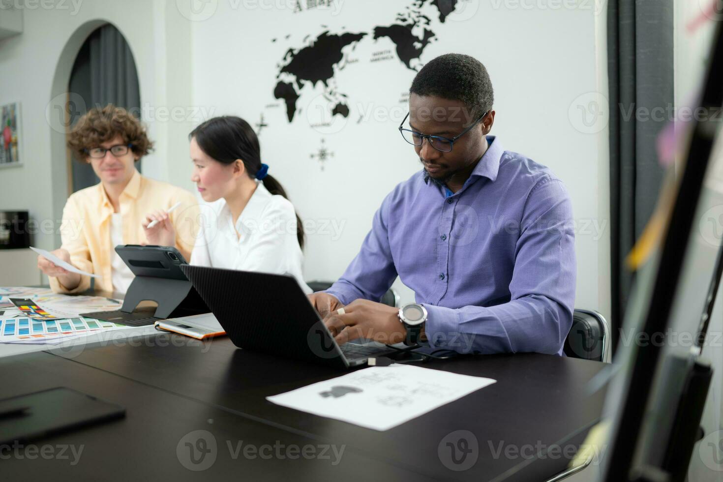 Multiethnic team of architects and designers are meeting to brainstorm design an application smartphone on a bright modern office working on a laptop. photo