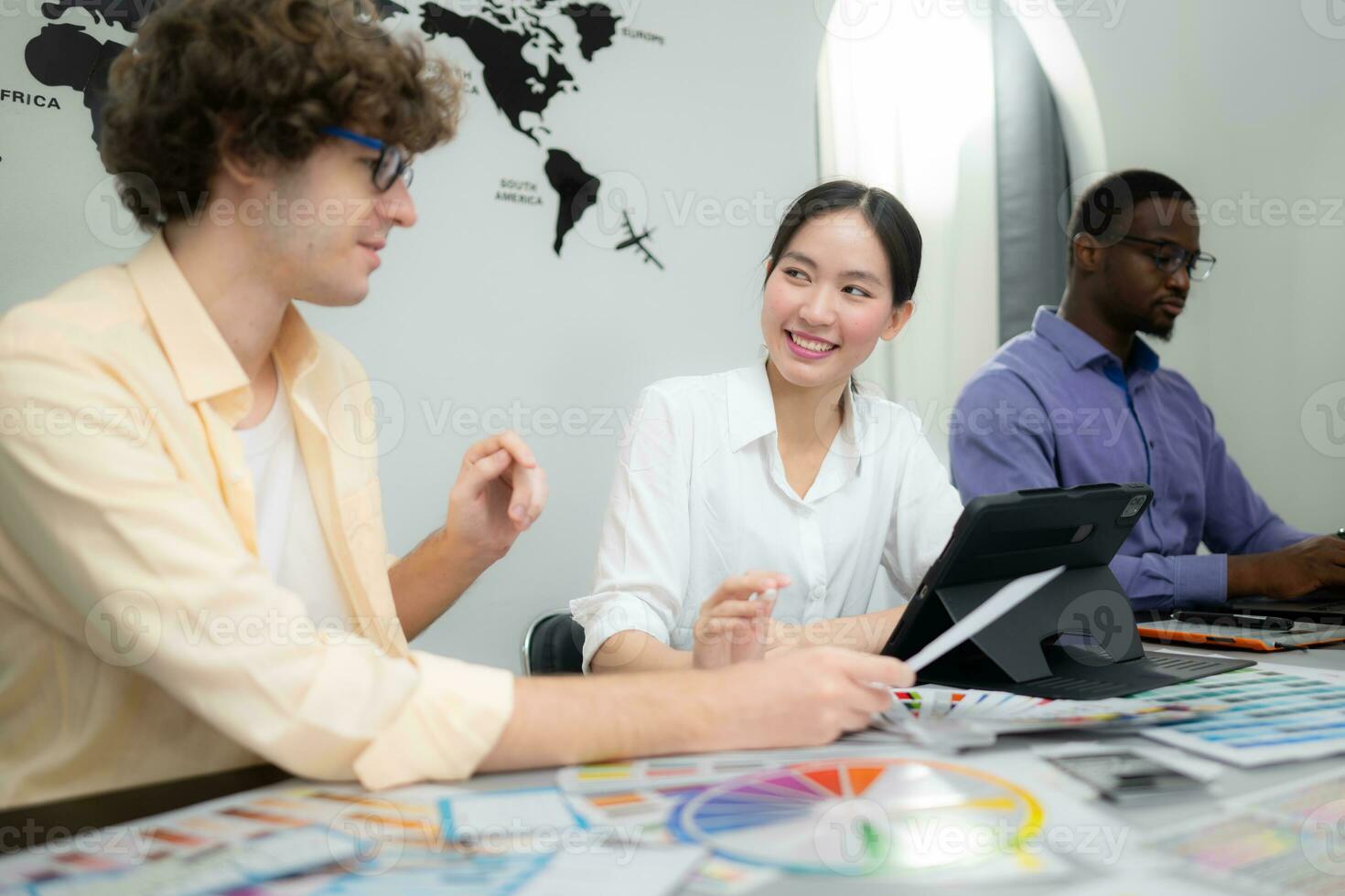 Multiethnic team of architects and designers are meeting to brainstorm design an application smartphone on a bright modern office working on a laptop. photo