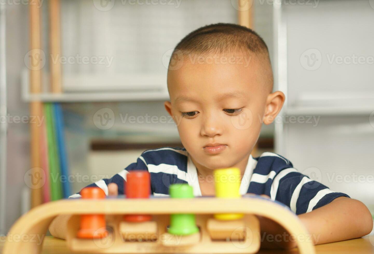 A boy plays with developmental toys on the table inside the house. photo