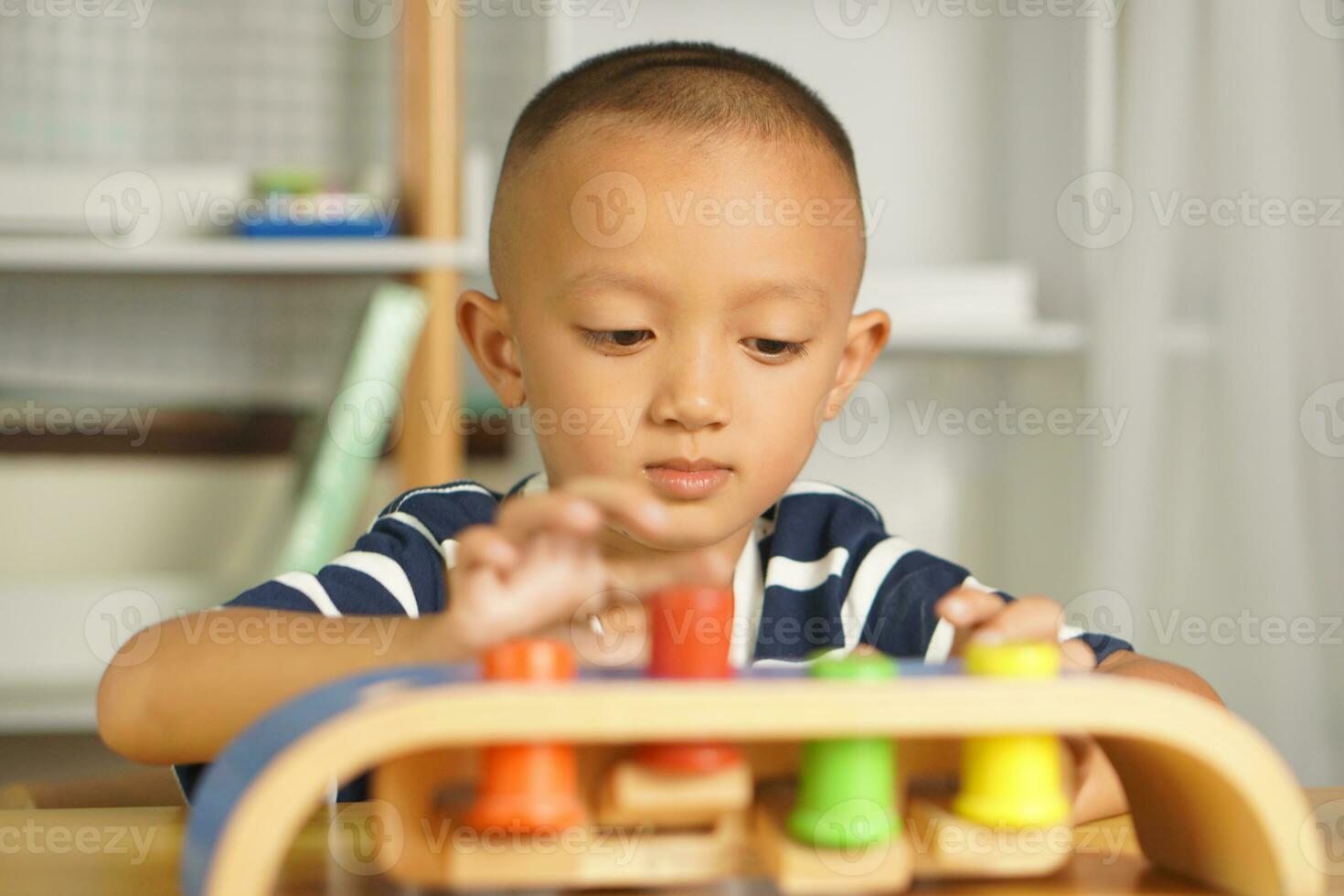 A boy plays with developmental toys on the table inside the house. photo