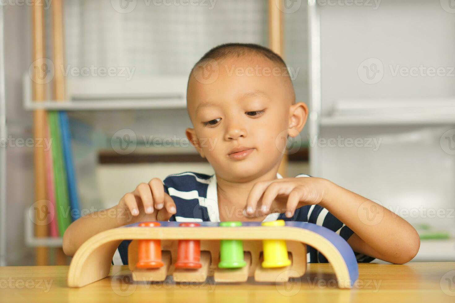 A boy plays with developmental toys on the table inside the house. photo