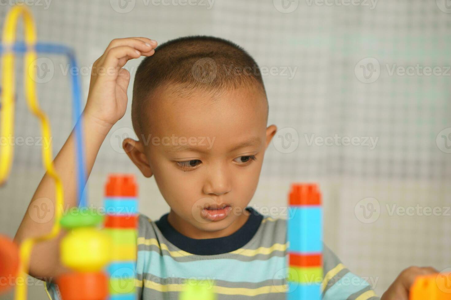 Asian boy playing with educational toys There are many beautiful colors on the table in the house. photo