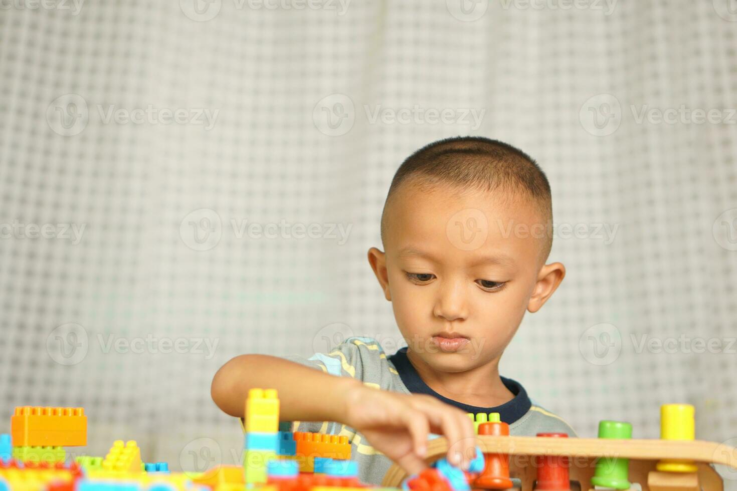 Asian boy playing with educational toys There are many beautiful colors on the table in the house. photo
