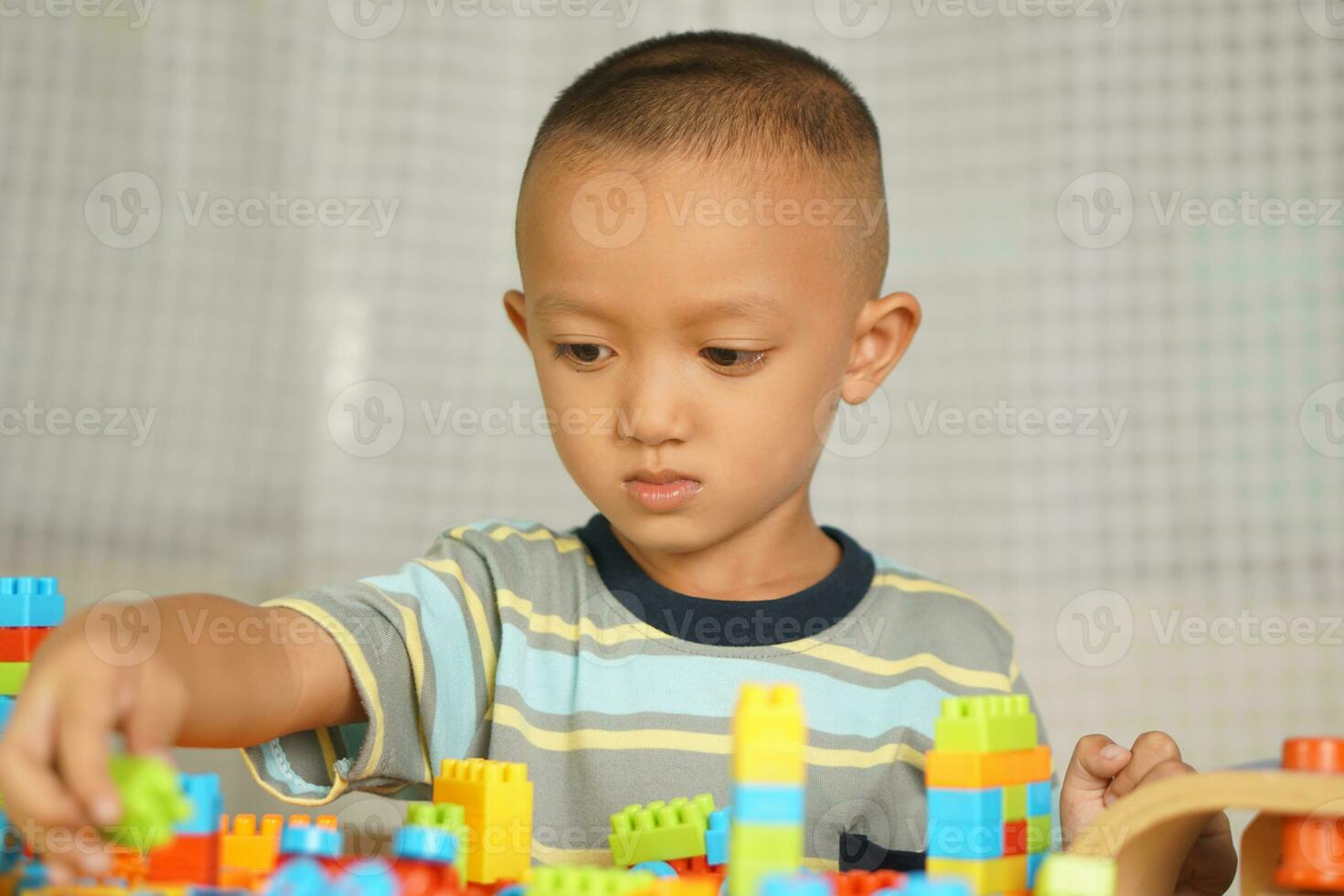 Asian boy playing with educational toys There are many beautiful colors on the table in the house. photo