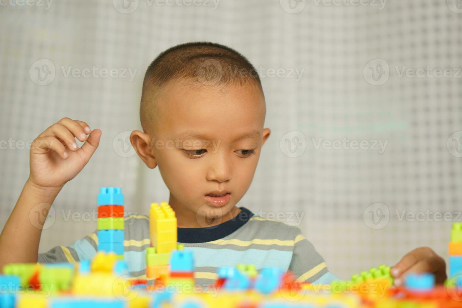Asian boy playing with educational toys There are many beautiful colors on the table in the house. photo