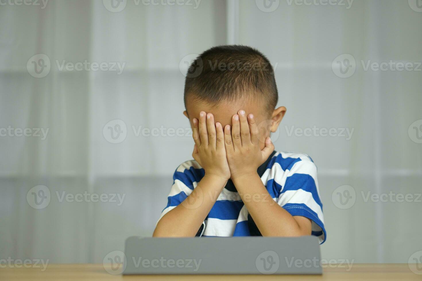 Boy has eye strain from looking at computer for a long time photo