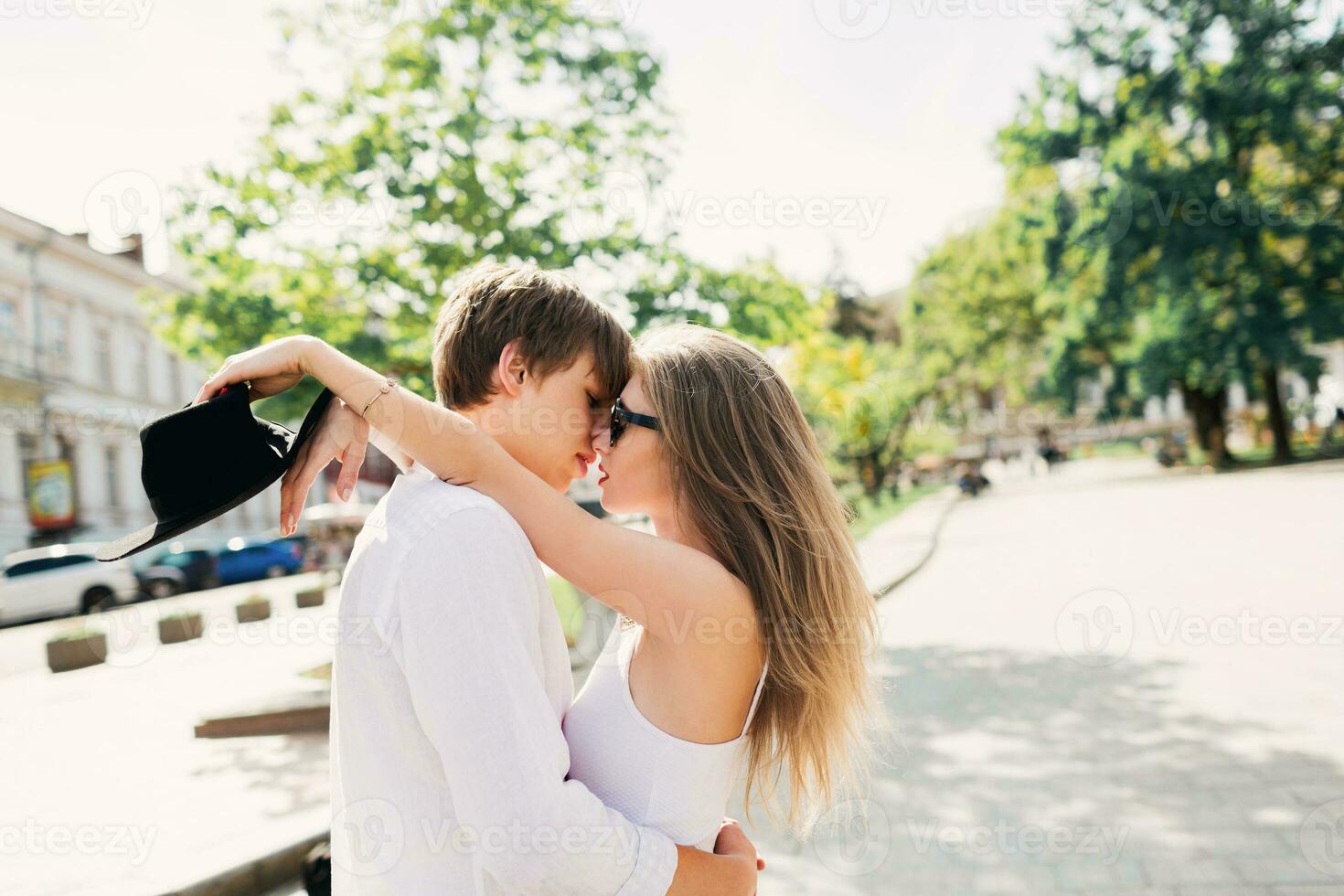 romántico emocional retrato de dos amantes, increíble Pareja en blanco primavera atuendo abrazando en calle, largo rubia pelos Clásico suave tonificado colores. foto