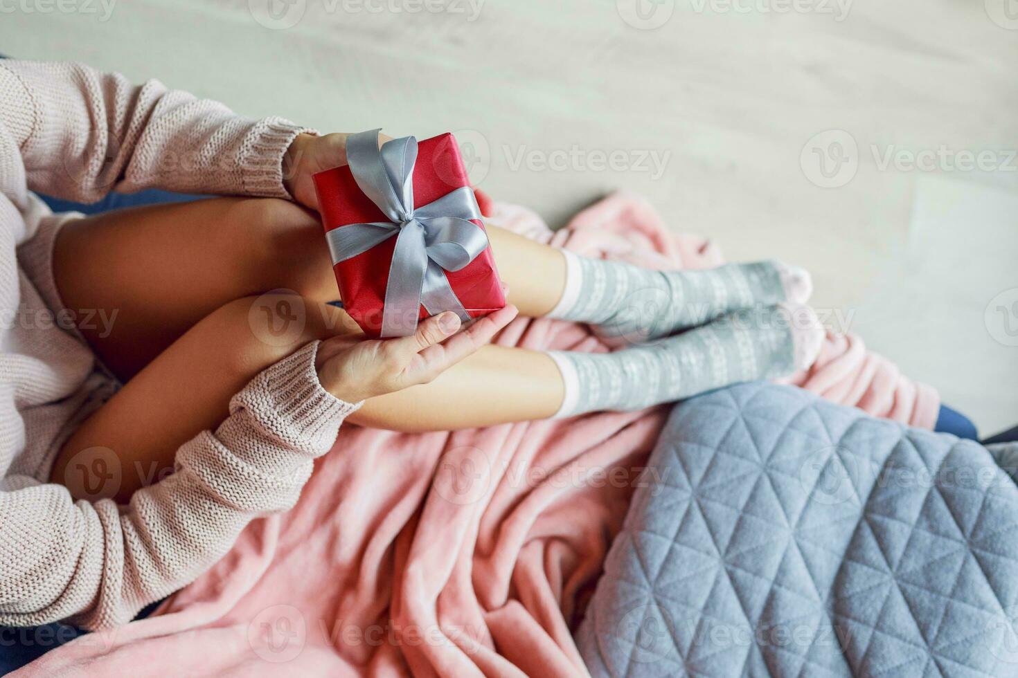 Top view  on pretty woman holding gift box, sitting on sofa in the home. Soft photo. Holiday concept. photo