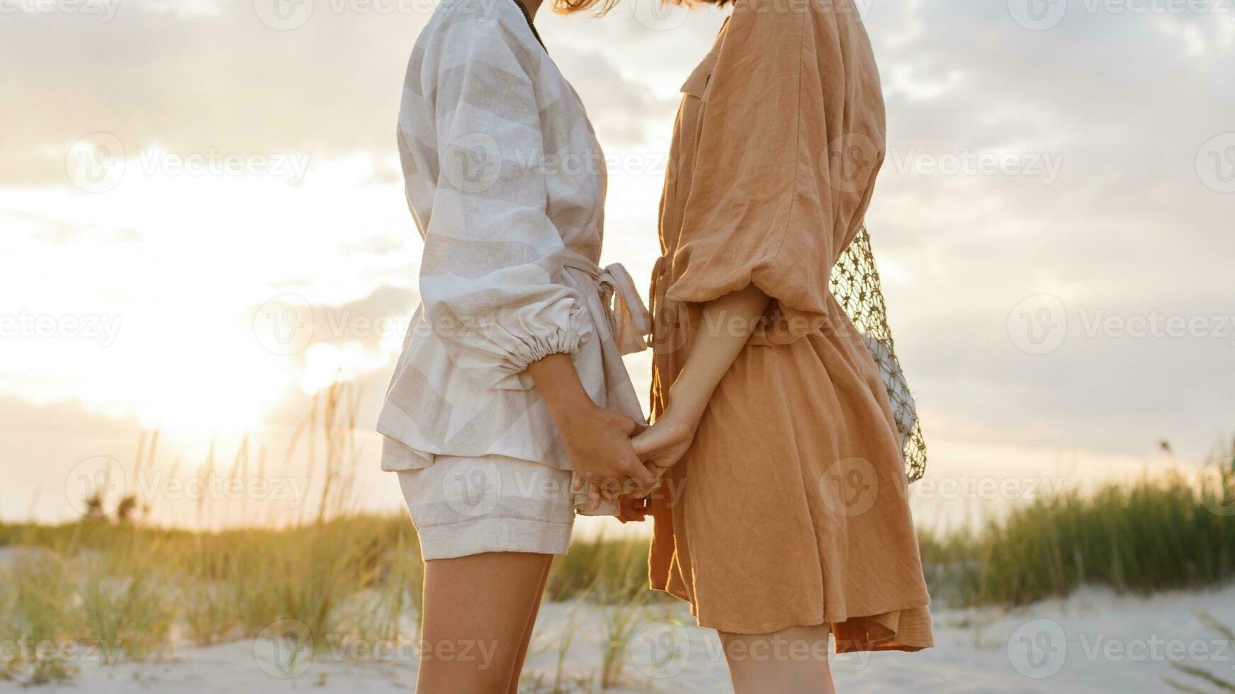 Summer fashion image of two  brunette european women in linen clothes posing on the beach photo
