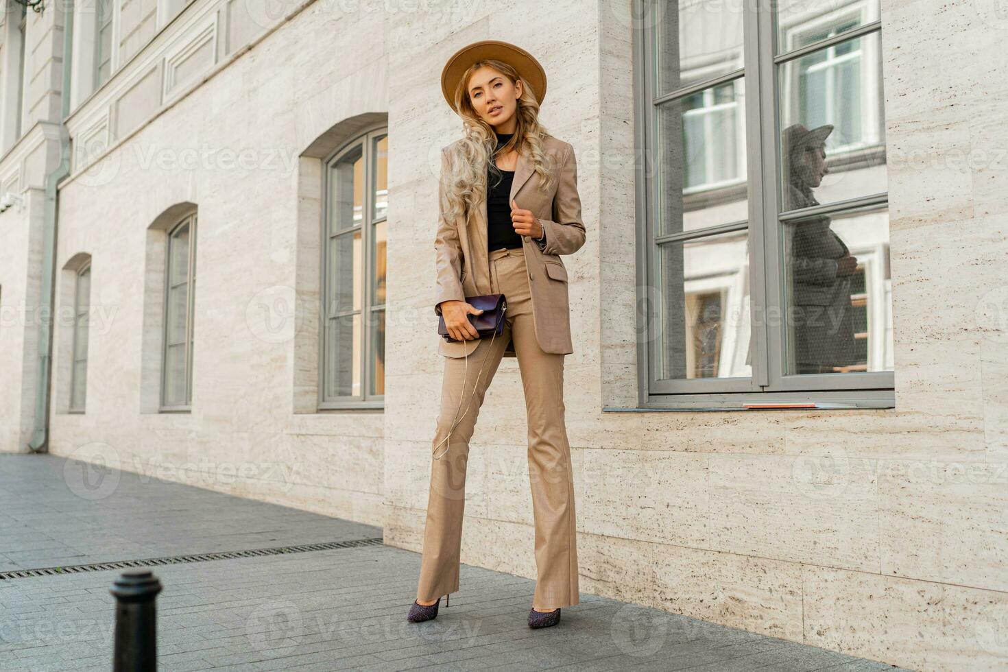 Stunning blond woman in casual leather suit walking on the street in Paris. Outdoor fashion style. Beige hat and purse .  Full lenght. photo