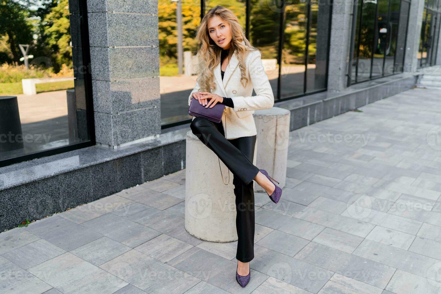 Elegant blond woman with perfect wavy hairs in casual  outfit with luxury purse posing over modern business center. photo