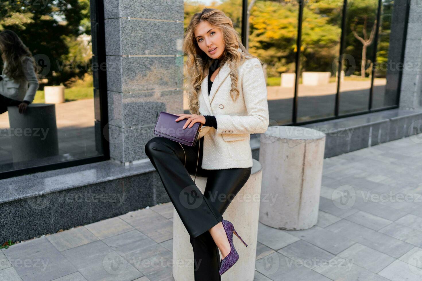 Elegant blond woman with perfect wavy hairs in casual  outfit with luxury purse posing over modern business center. photo