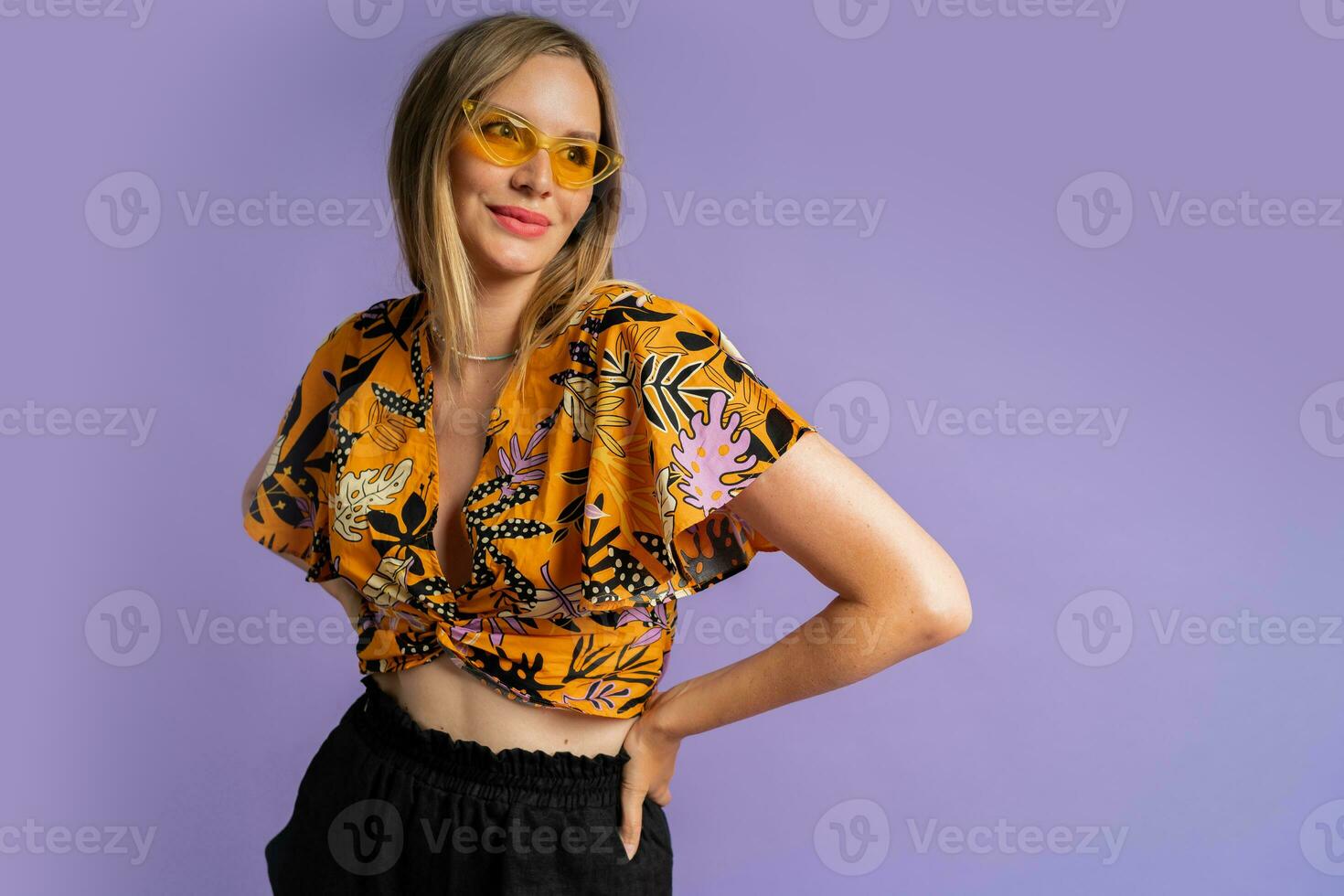 Studio   close up fashion  portrait  of pretty blond woman in stylish top and  linen shorts posing on purple background. photo