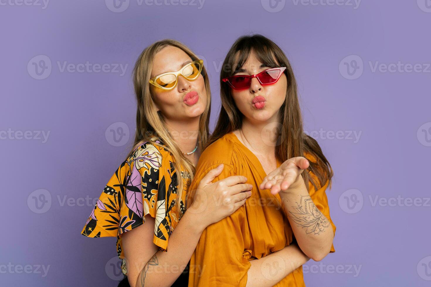 cerca arriba retrato de dos elegante mujer en Gafas de sol y de moda verano ropa posando en púrpura fundamento en estudio. foto