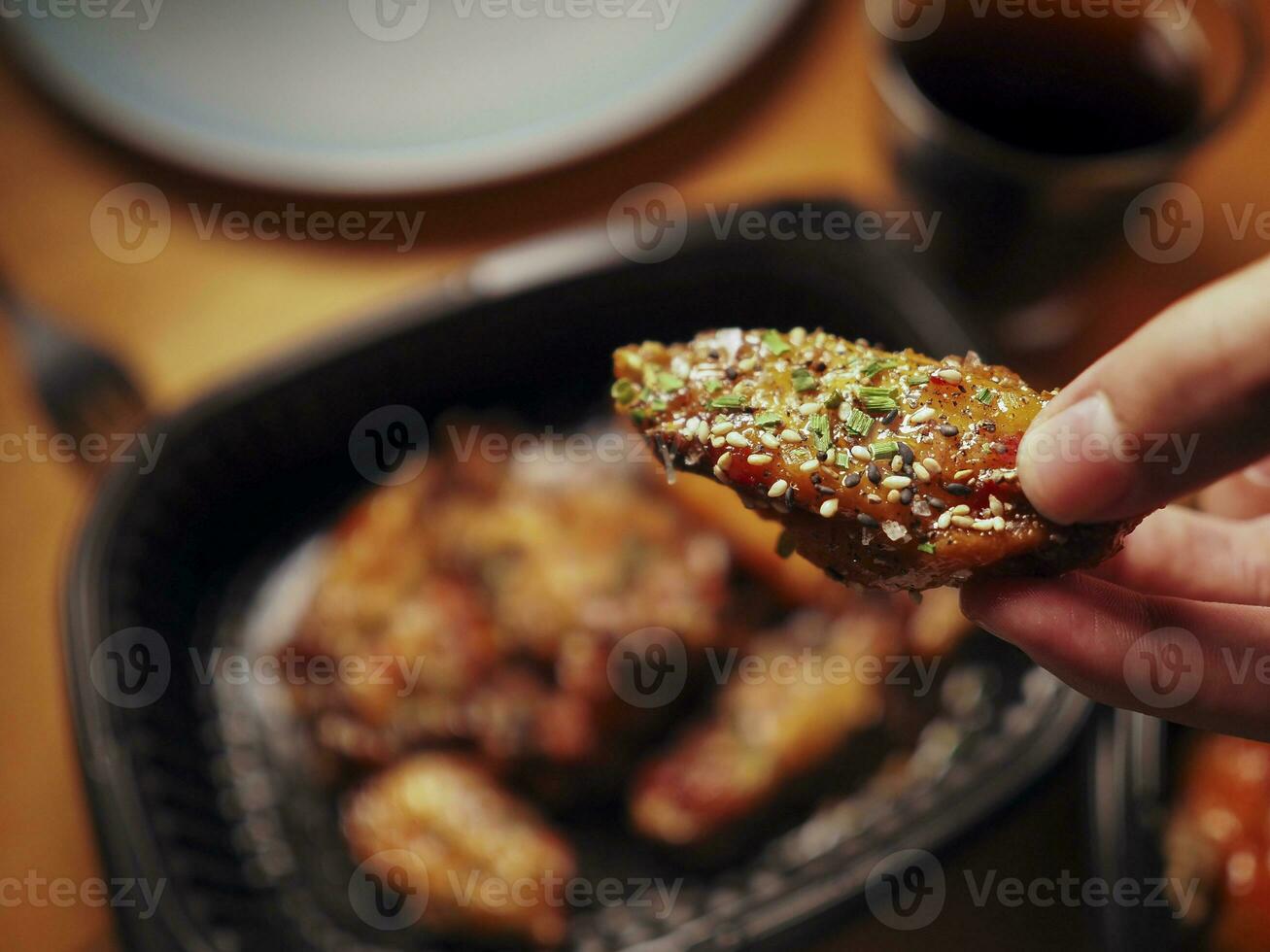 A man picking up a chicken wing in Korean style. Asian food. Delivery concept photo