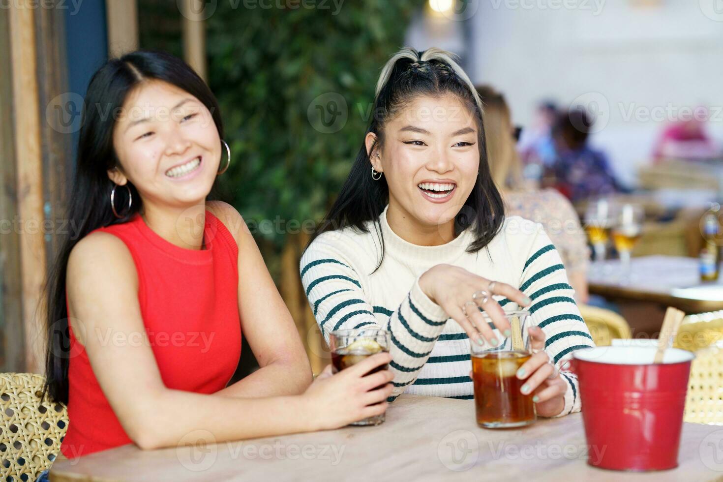 Positive Asian girls resting in cafe with drinks photo