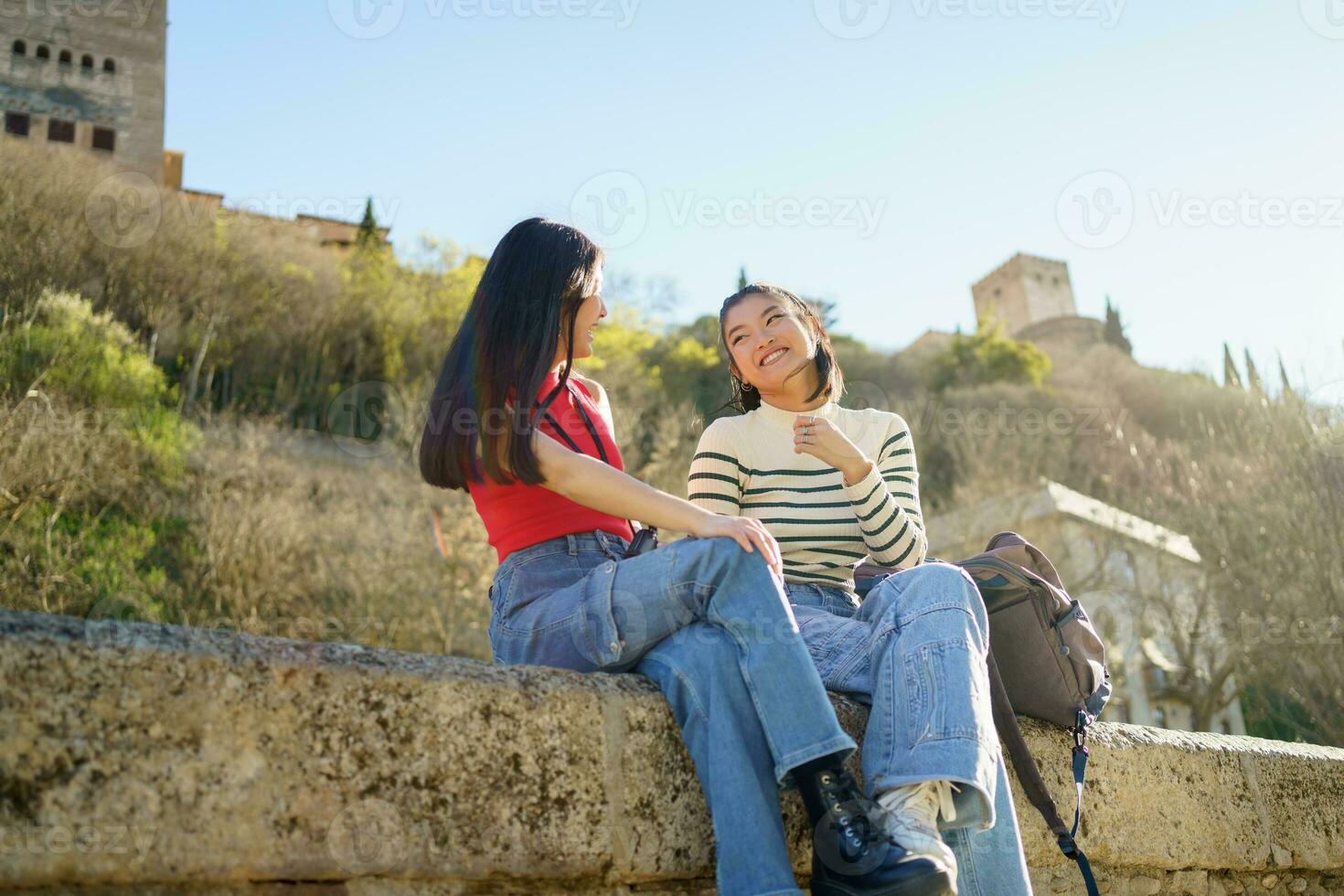Happy Asian women laughing on stone border during trip photo