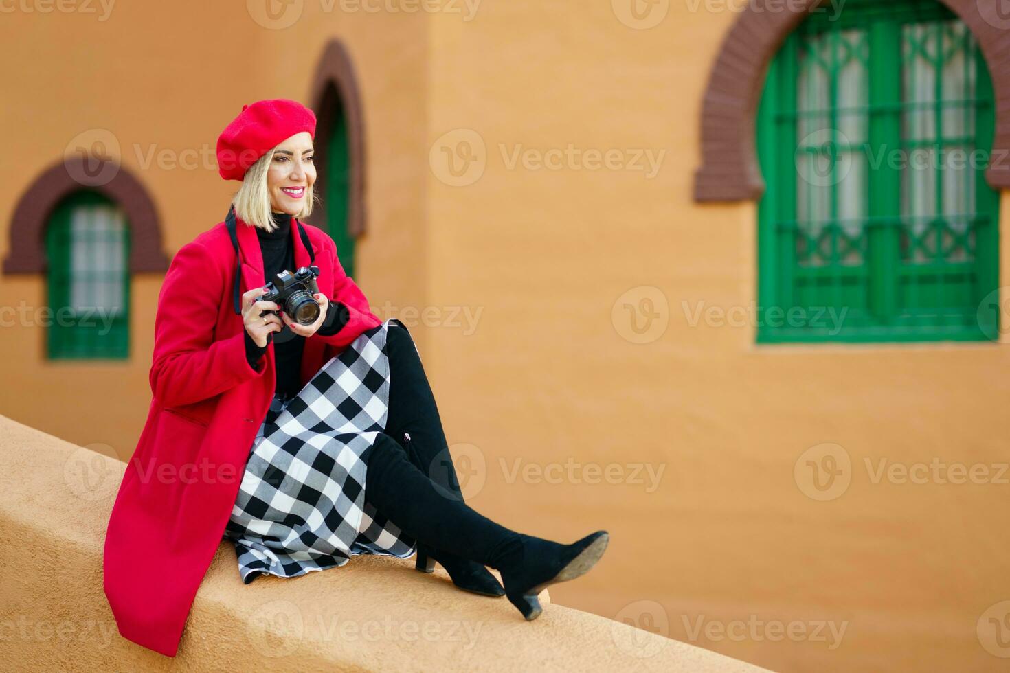 Stylish woman with photo camera on border of building