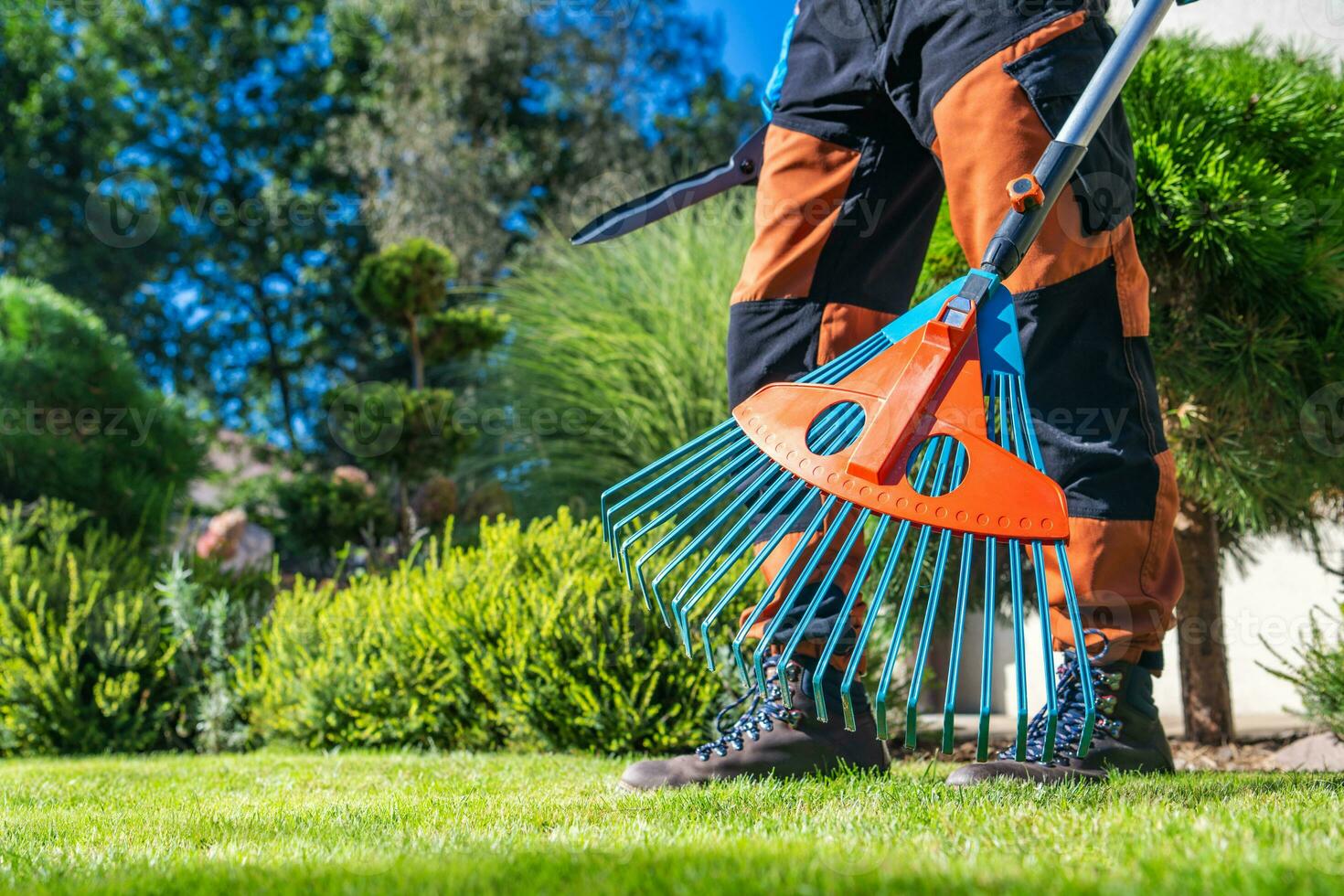 jardín trabajador con el plastico moderno rastrillo en su manos foto