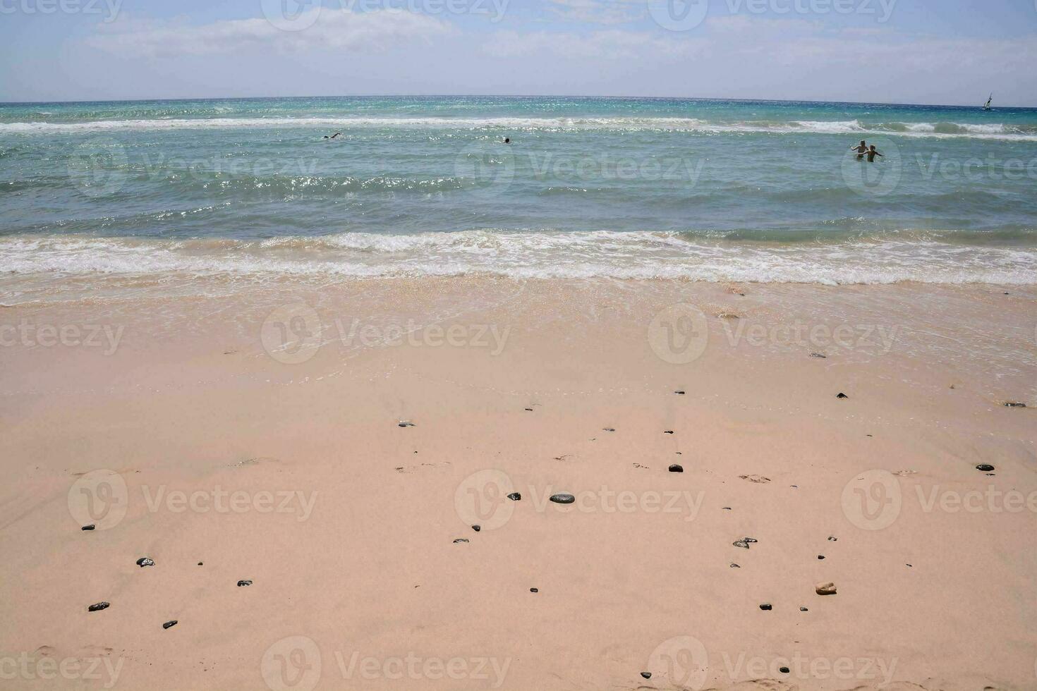 a sandy beach with people in the water photo