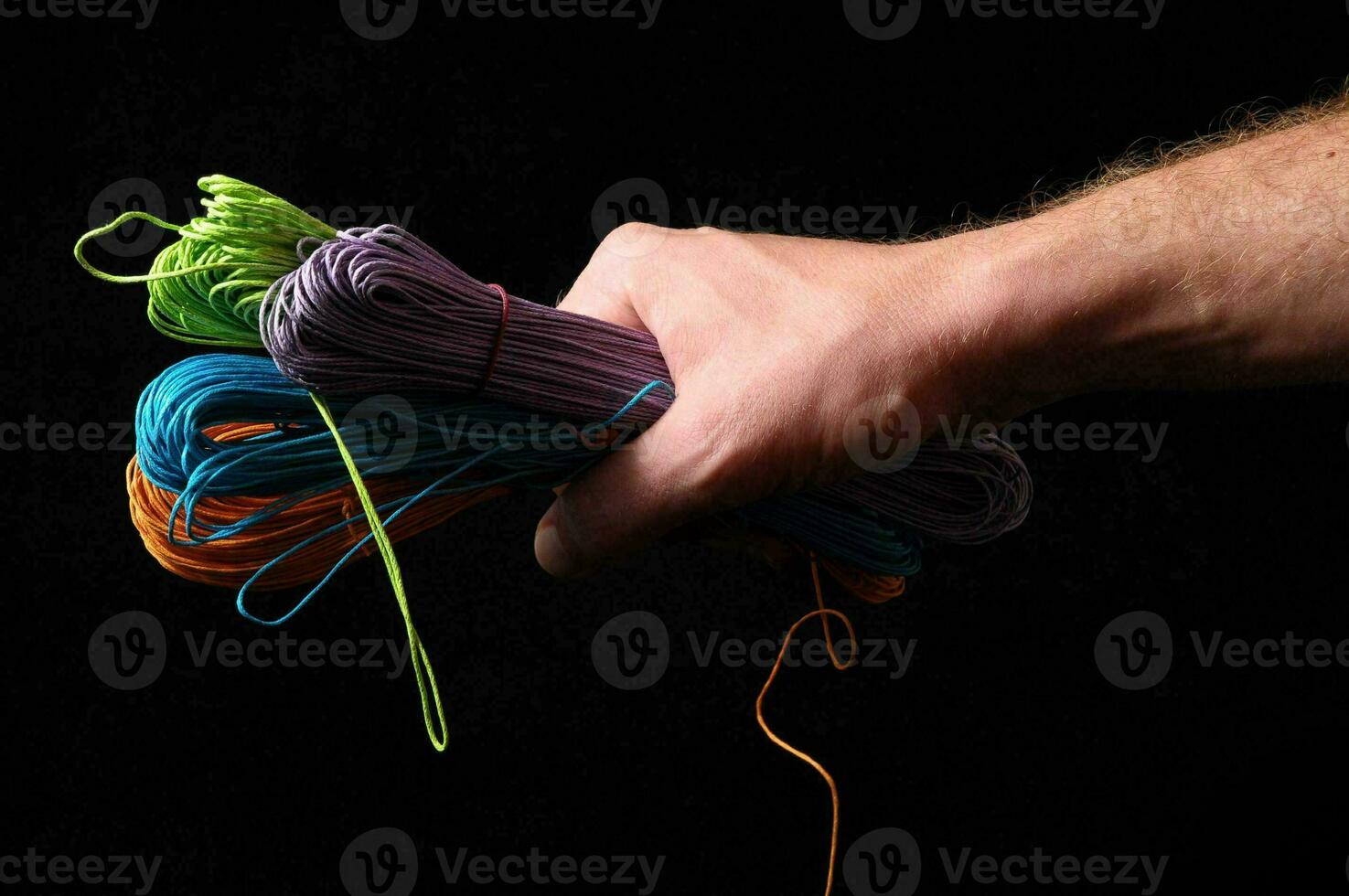 a hand holding a bunch of colorful string photo