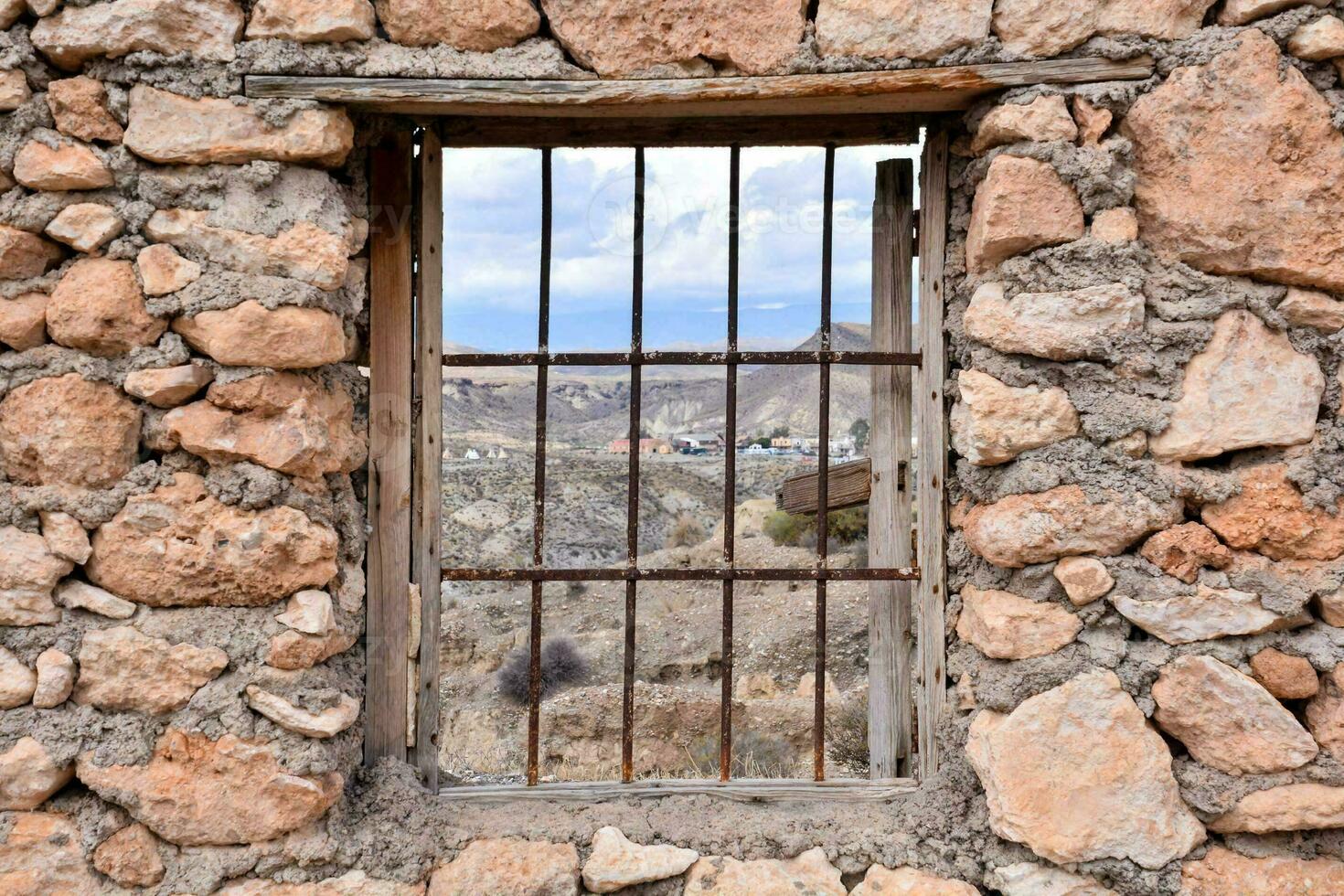 un ventana en un Roca pared con barras foto