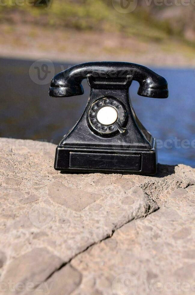 un antiguo teléfono en un rock foto